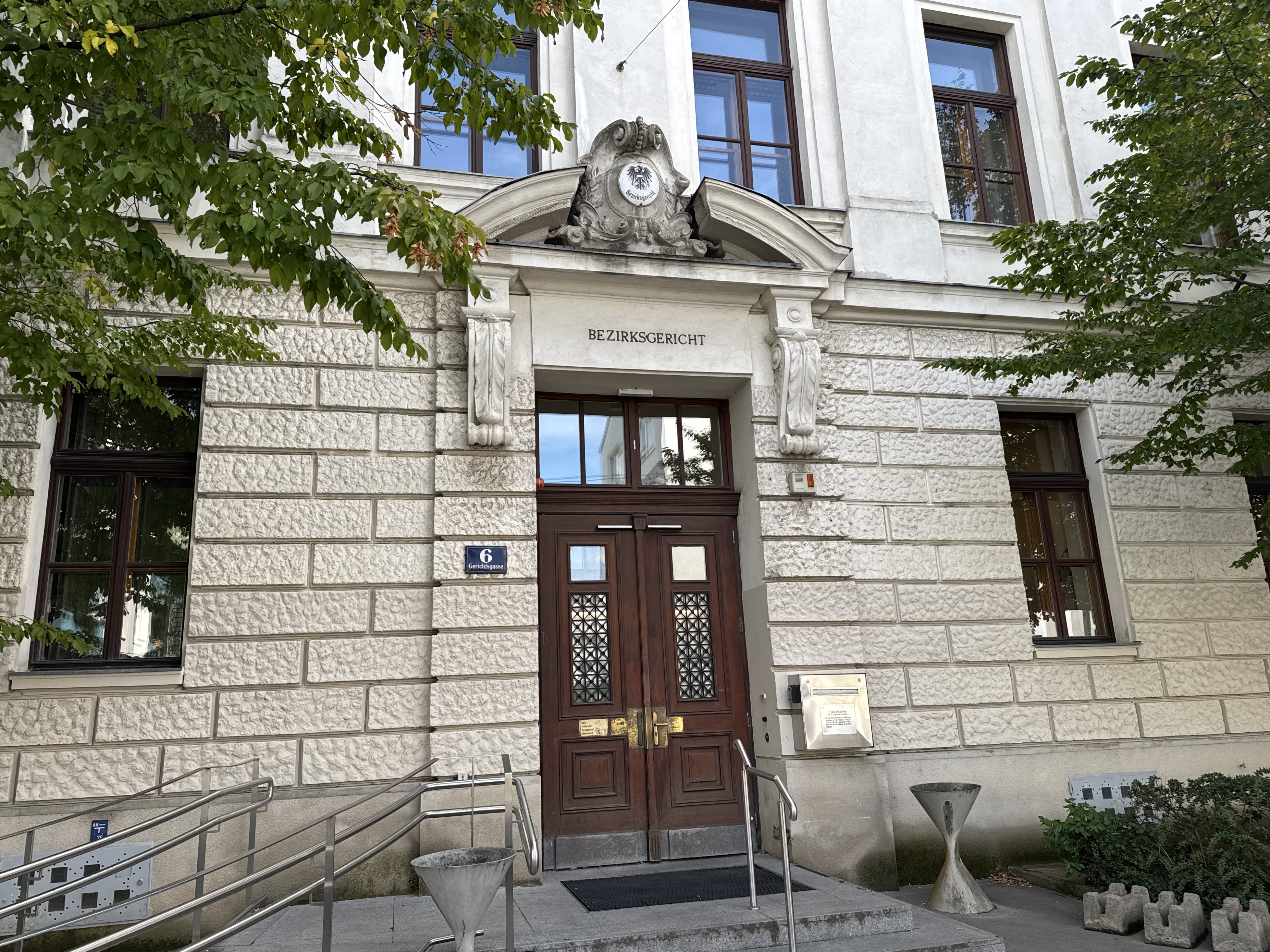 Eingang des Bezirksgerichts in der Gerichtsgasse 6: historisches Gebäude mit Rustika-Fassade, Holztür und Treppe mit Geländer
