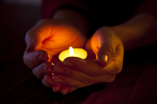 Hände halten eine Kerze im Gebet. / iStock/TSchon Hände halten eine Kerze im Gebet.