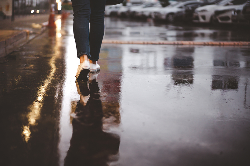 Frau geht alleine auf nasser Straße