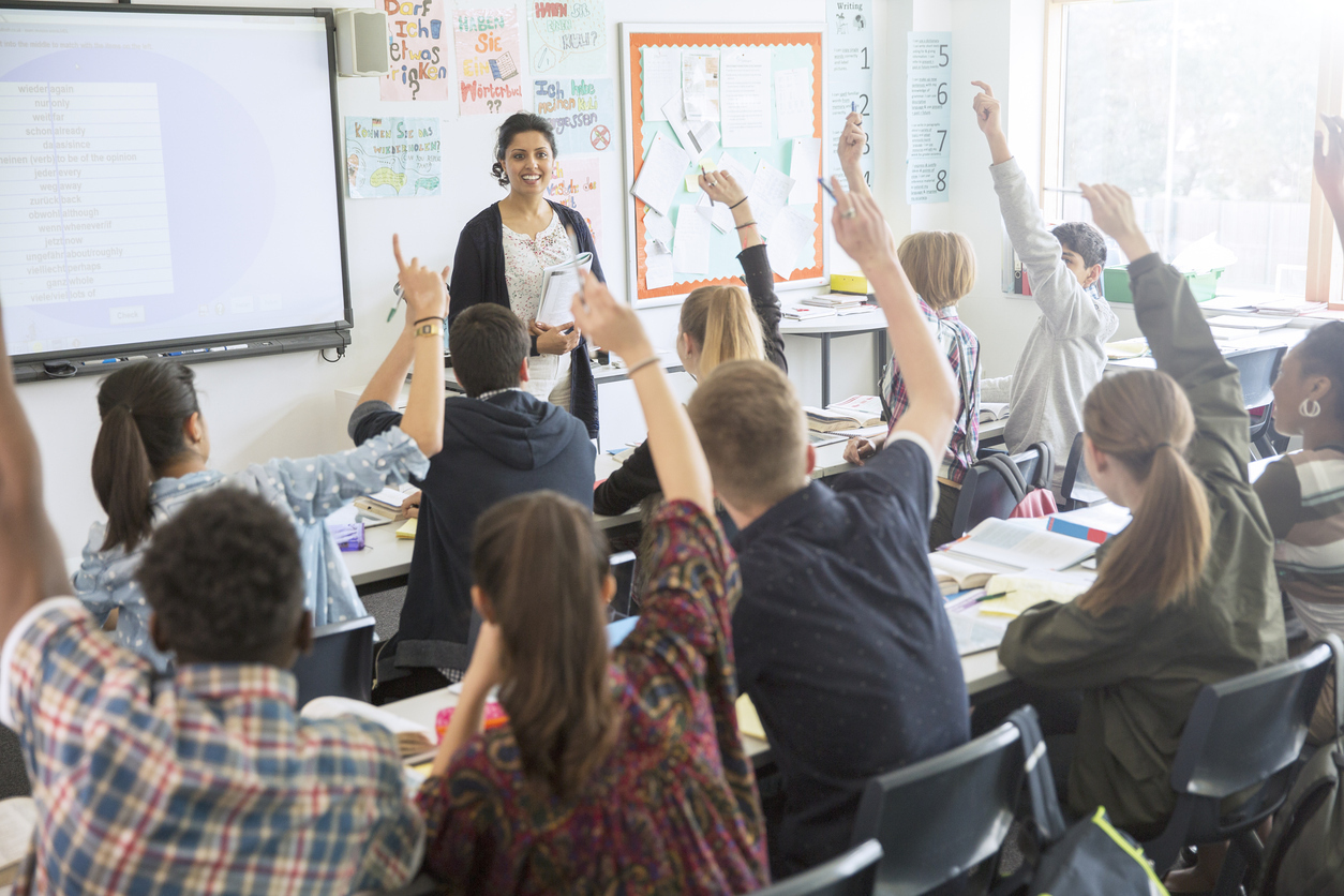 Unterrichtsstunde mit Schüler:innen die aufzeigen.