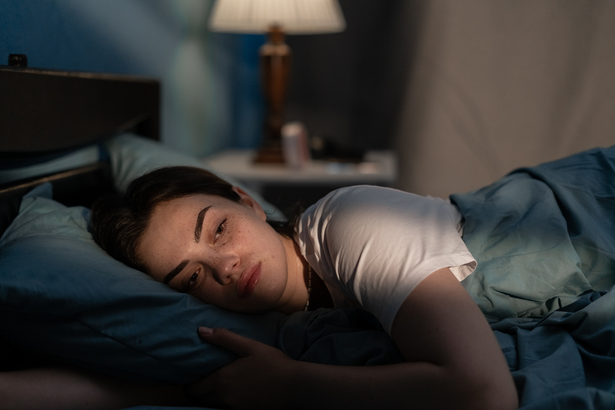 Erschöpfte junge Frau im Bett.