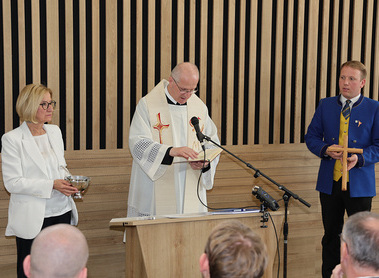 Pfarrer P. Michael Fritz OSB segnete das Musikheim. Spontan assistierte LH Johanna Mikl-Leitner mit dem Weihwasserkessel. Rechts Obmann Lukas Rohrer mit einem Holzkreuz für´s Musikheim.