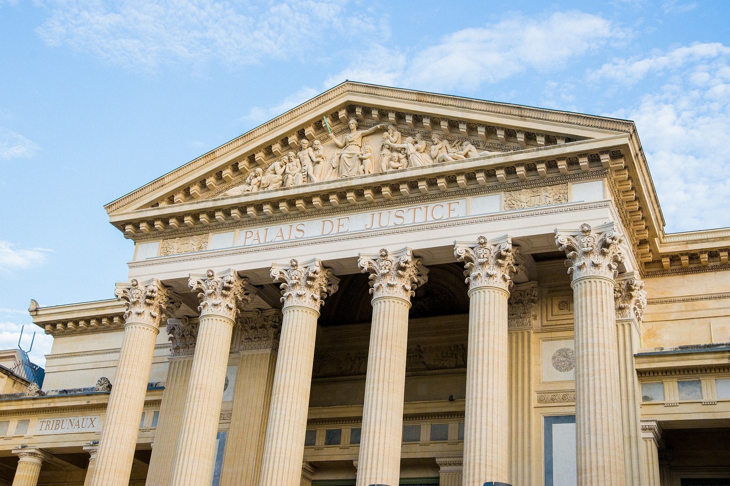 Klassizistische Fassade eines Justizpalastes mit Säulen und der Inschrift „Palais de Justice'