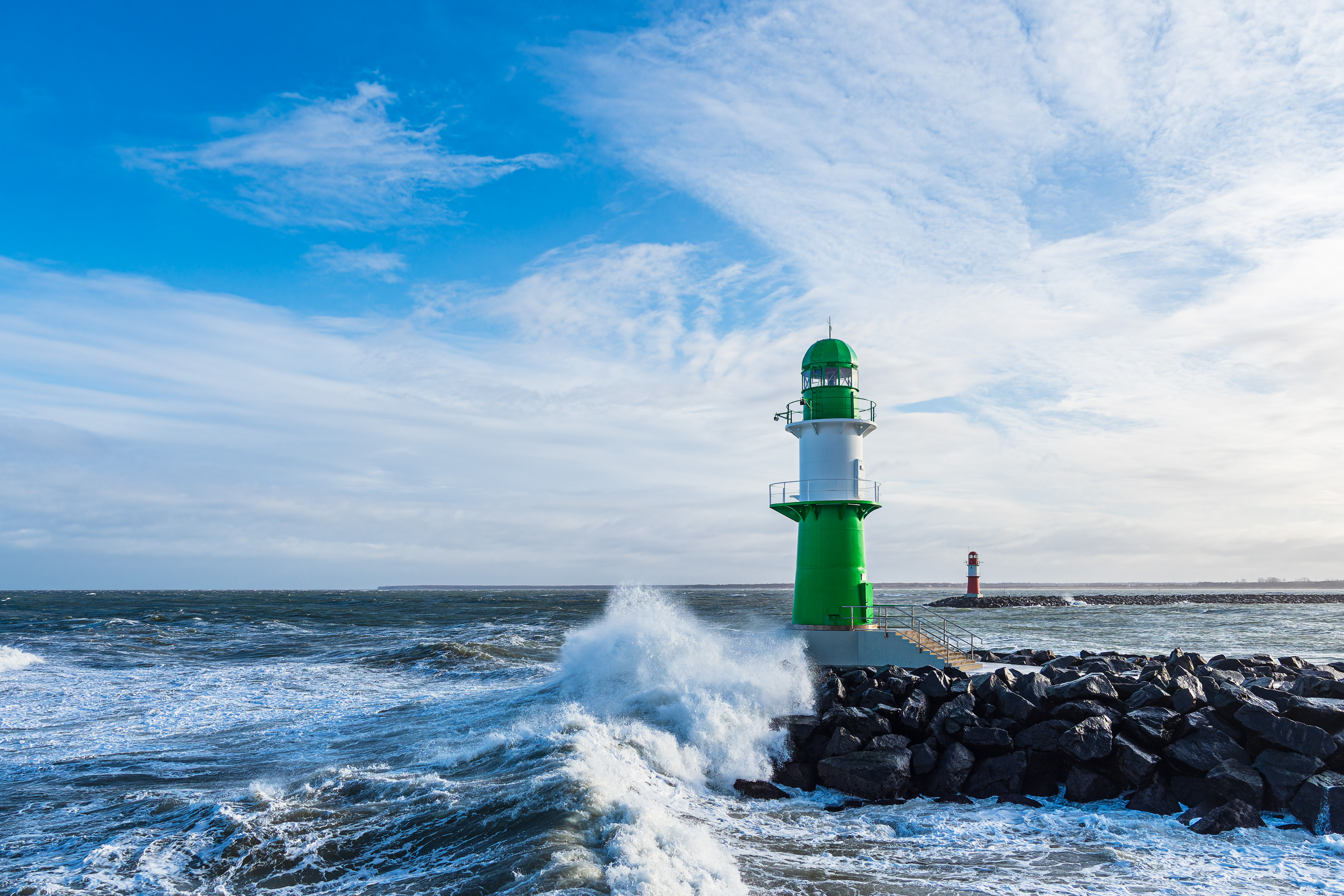 Pier and waves on shore of the Baltic Sea in Warnemuende, Germany.
