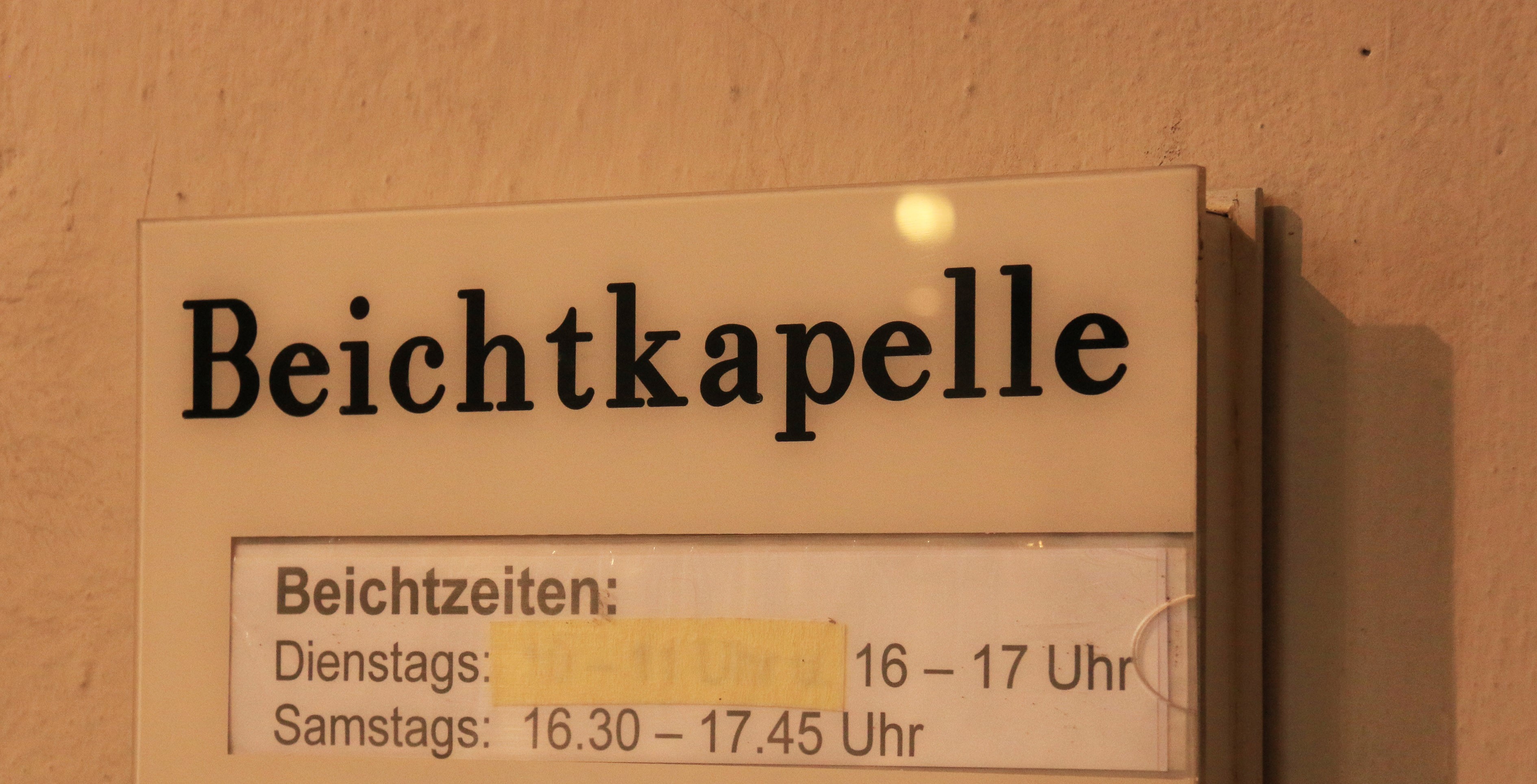 Schild mit der Aufschrift 'Beichtkapelle' und Beichtzeiten.