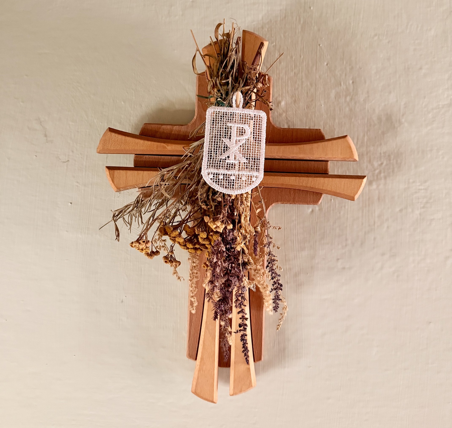 Holzkreuz mit Trockenblumen und Fahne mit Christusmonogramm