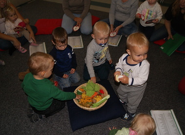 Die Kinder betrachten fasziniert das Spielobst und die Kürbise.