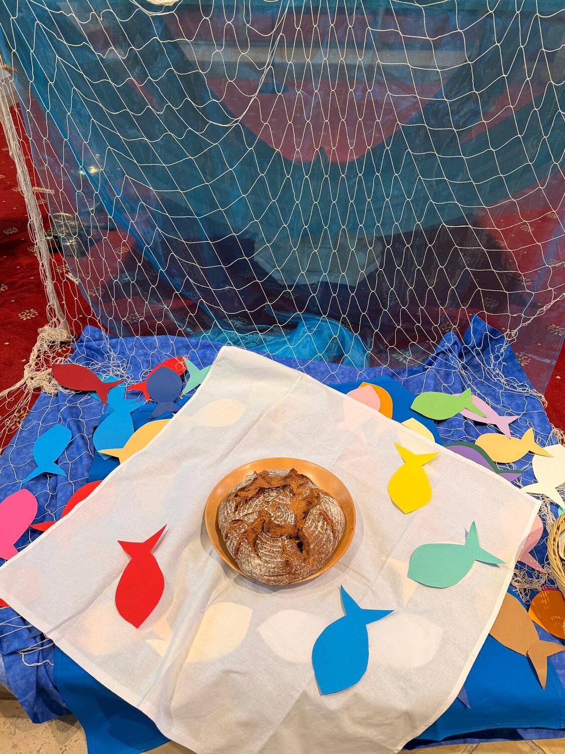 Brot, bunte Papierfische vor Altar