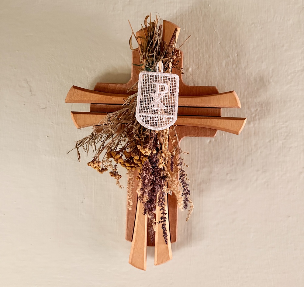 Holzkreuz mit Trockenblumen und Fahne mit Christusmonogramm