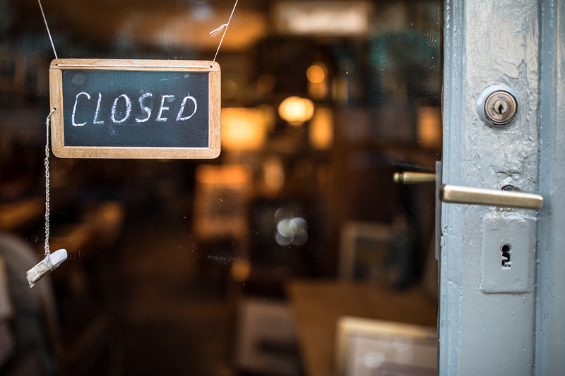 Closed - sign hanging on glass door of a shop in a city