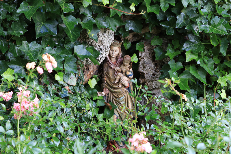 Eine Statue der Gottesmutter Maria in einem Garten.