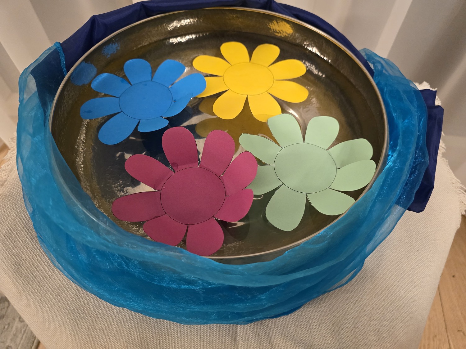 Schale mit Papierblumen im Wasser
