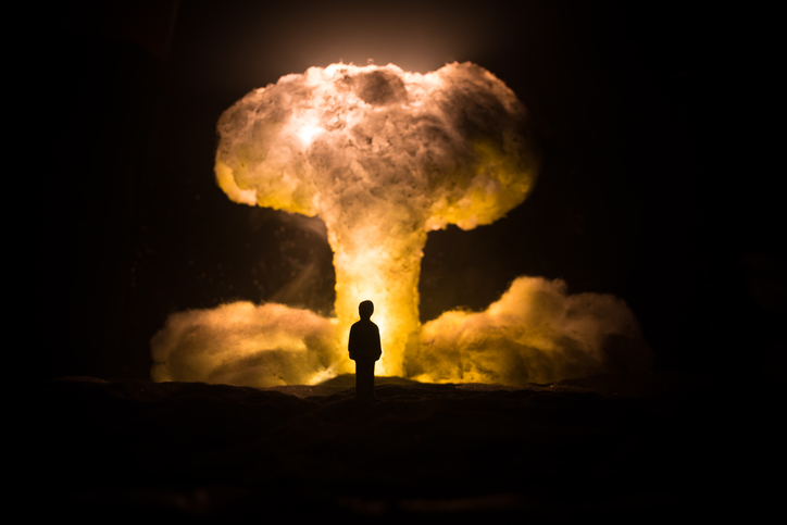 Nuclear war concept. Explosion of nuclear bomb. Creative artwork decoration in dark. Silhouette of a person against giant mushroom cloud of atomic explosion. Selective focus