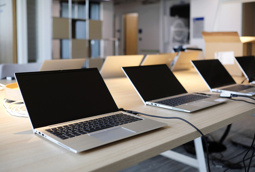 Row of laptops being prepared and set up for new employees in a company