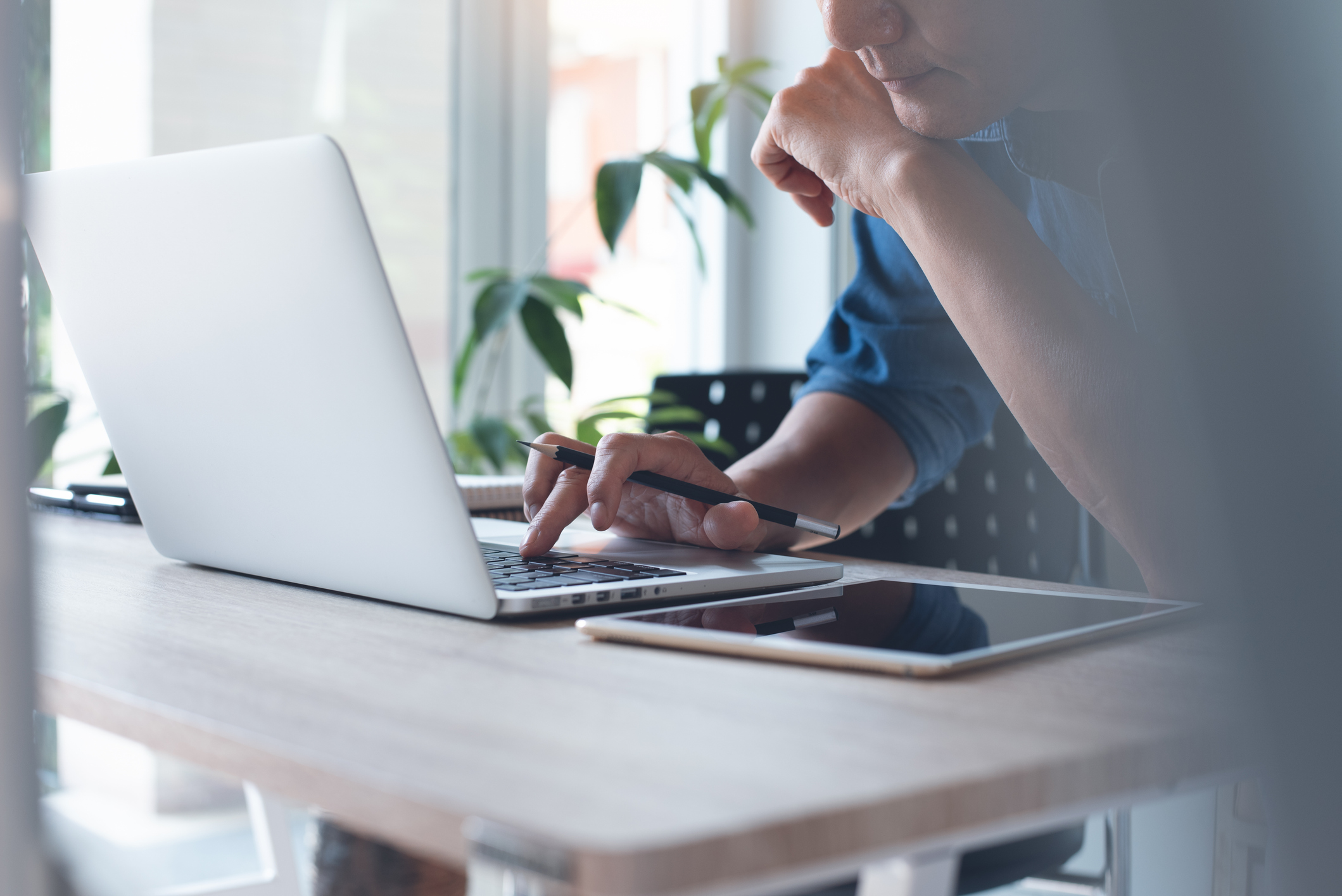 Smart asian casual business man, freelancer, graphic designer working on laptop computer, browsing internet with digital tablet on table at home office. Work from home, teleworking concept