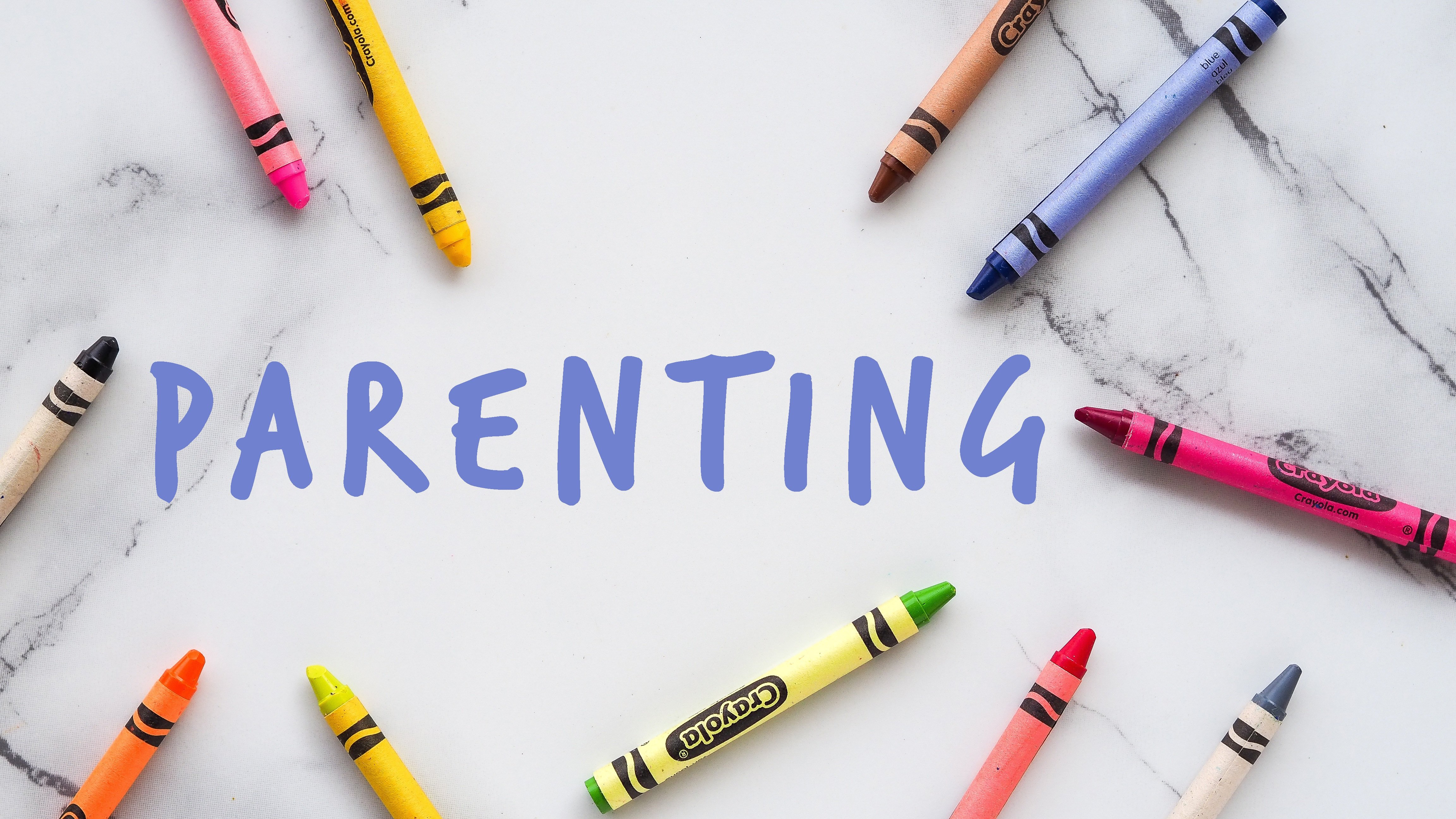 Bunte Wachsmalstifte liegen kreisförmig um den Schriftzug „Parenting', Symbolbild für Beratung zu Elternrechten und Erziehungsfragen.