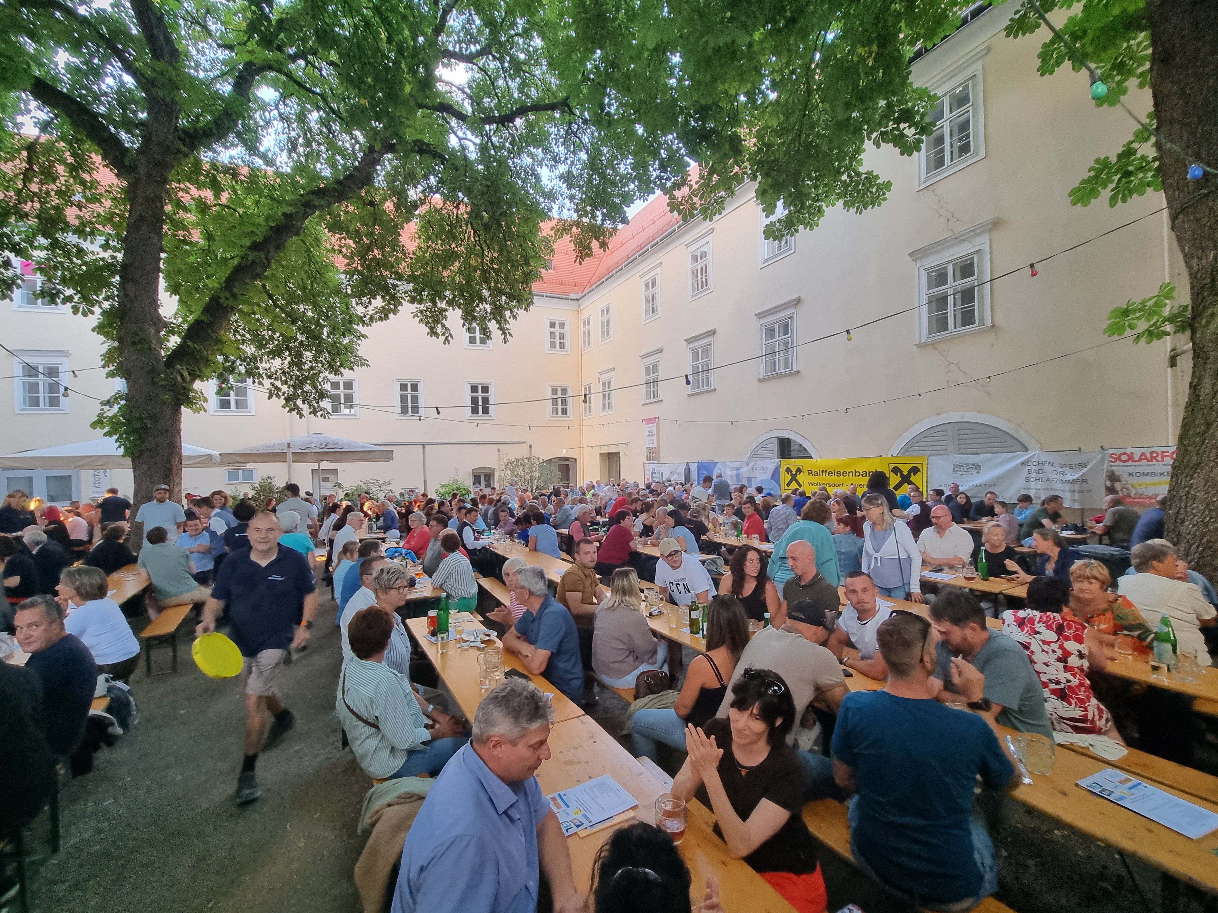 Leute sitzen auf Tischen im Schlosshof in Wolkersdorf