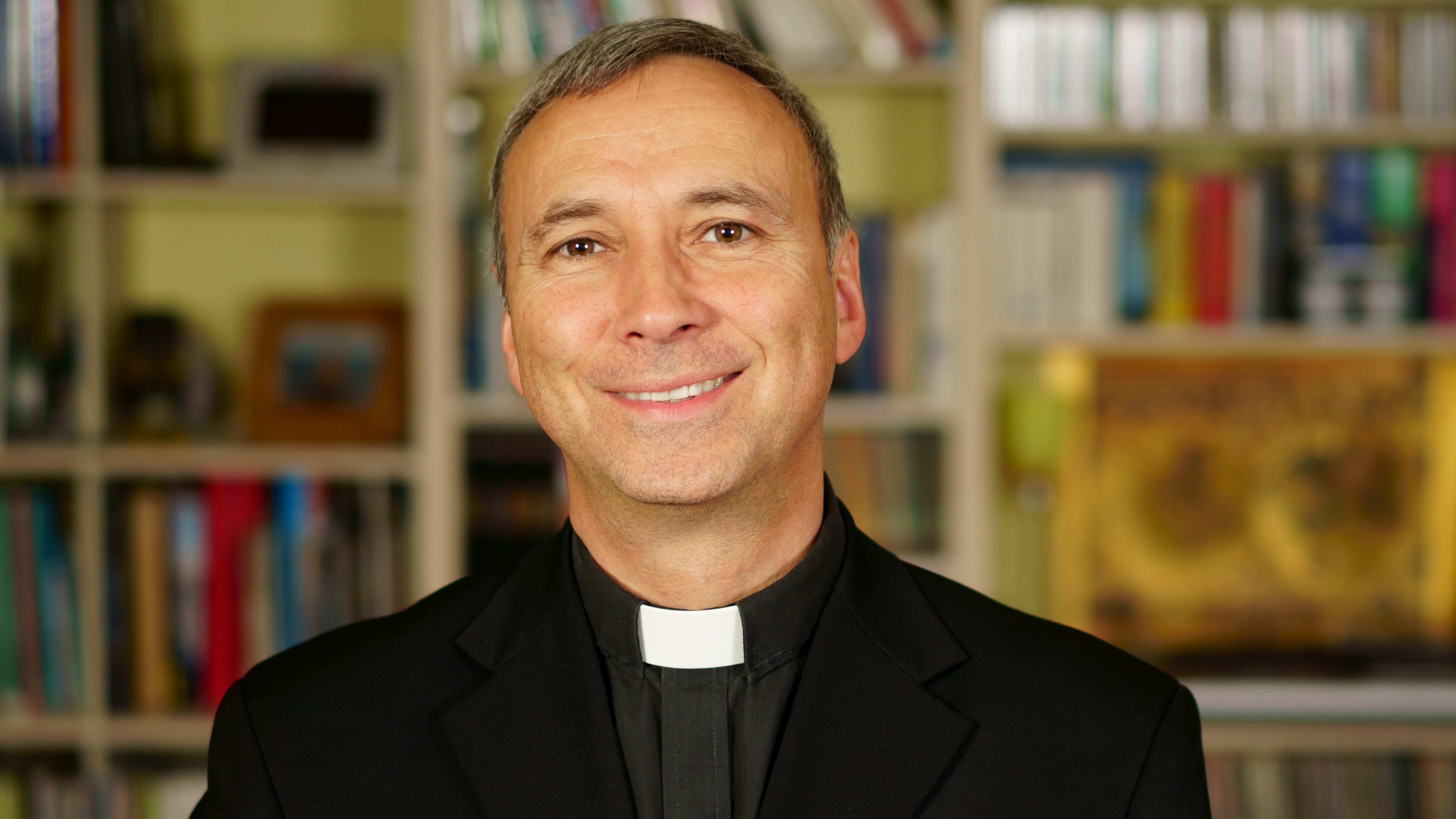 A priest, abbe, father in his library. / amoniak films, Amoniak A portrait of a good looking serious catholic priest. He looks at us with interest, pensiveness, proselytising, joy, happyness, trust and peacefulness.