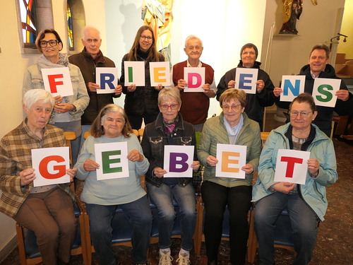 Menschen formieren das Wort Friedensgebet