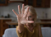 Female palm close up with mature model lady in home background. Scared concerned middle aged woman showing hand stop gesture at camera, meaning no violence, abuse, expressing protest against force