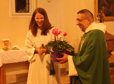Eine Ministrantin überreicht seitens der Pfarre Blumen.