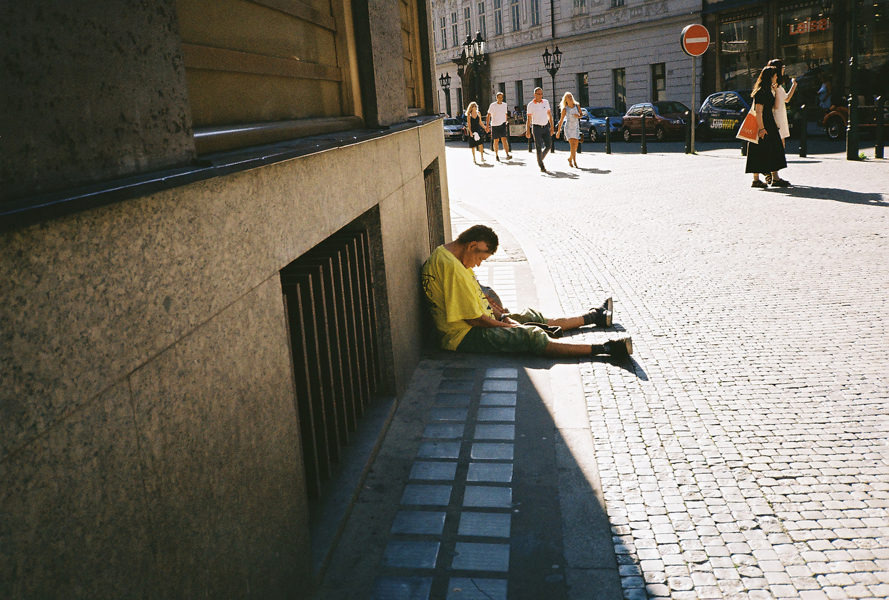 Obdachloser im Schatten auf einer Straße.