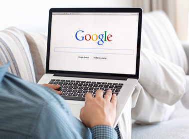 Ein Mann sitzt auf der Couch und googelt.