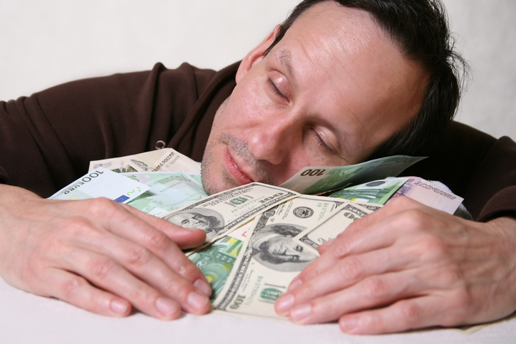 Mann schläft auf seinem Geld.
