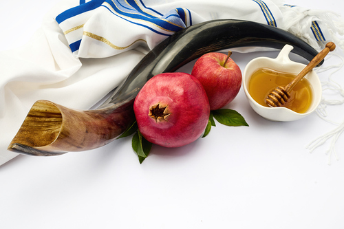 Shofar, apples, pomegranate, honey and a tallit representing Jewish New Year traditions.